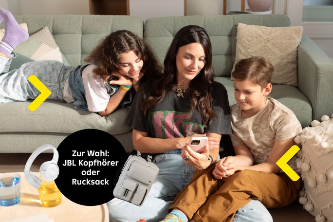 Frau mit Kindern auf dem Sofa  mit dem Text Zur Wahl: JBL Kopfhörer oder Rucksack. Mit Darstellung der Kopfhörer und des Rucksacks