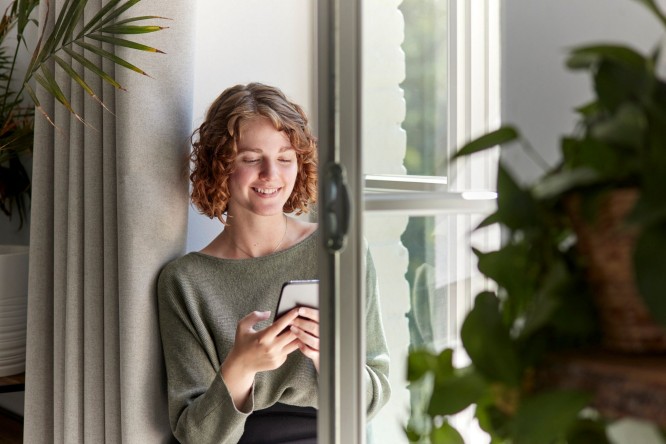 Laptop Darstellung mit einem Mail Zeichen auf dem Bildschirm auf gelbem Hintergrund. Der Laptop hängt an einem Haken.